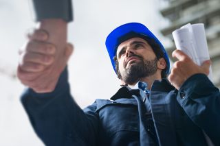 © Minerva Studio - stock.adobe.com Foto: Handschlag mit Bauarbeiter